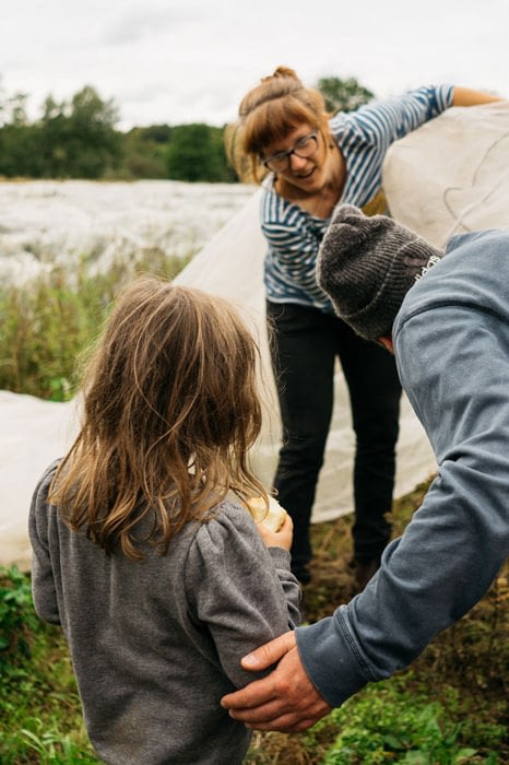 Gemüsegärtnerin zeigt einem interessierten Kind die angebauten Kulturen